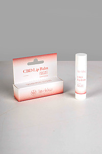 Cardboard rectangular packaging and an elongated oval lip balm cylinder on a table surface