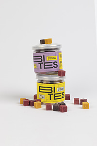 Eaten multi-colored freeze-dried fruit snack cubes stacked next to each other in cylindrical packaging containers