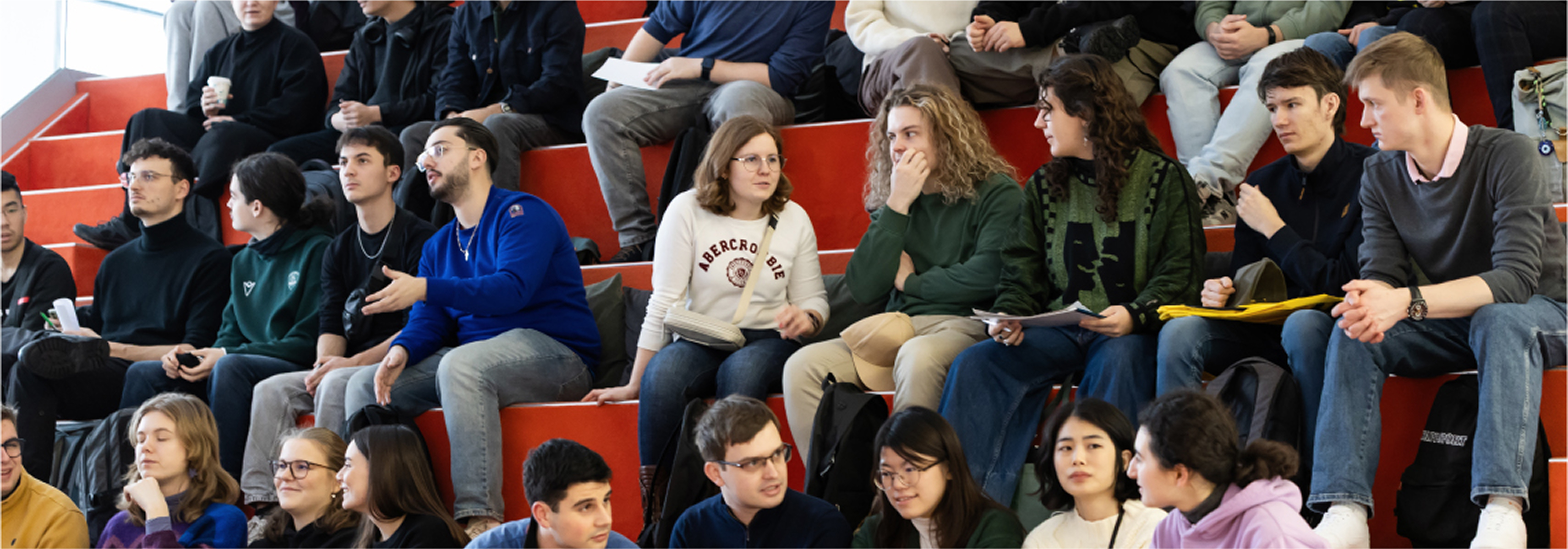 A diverse group of KTU students sitting together on tiered seating, talking, listening and interacting in a university environment, representing the strategic direction &ldquo;Engaging and Creative Community&rdquo;.