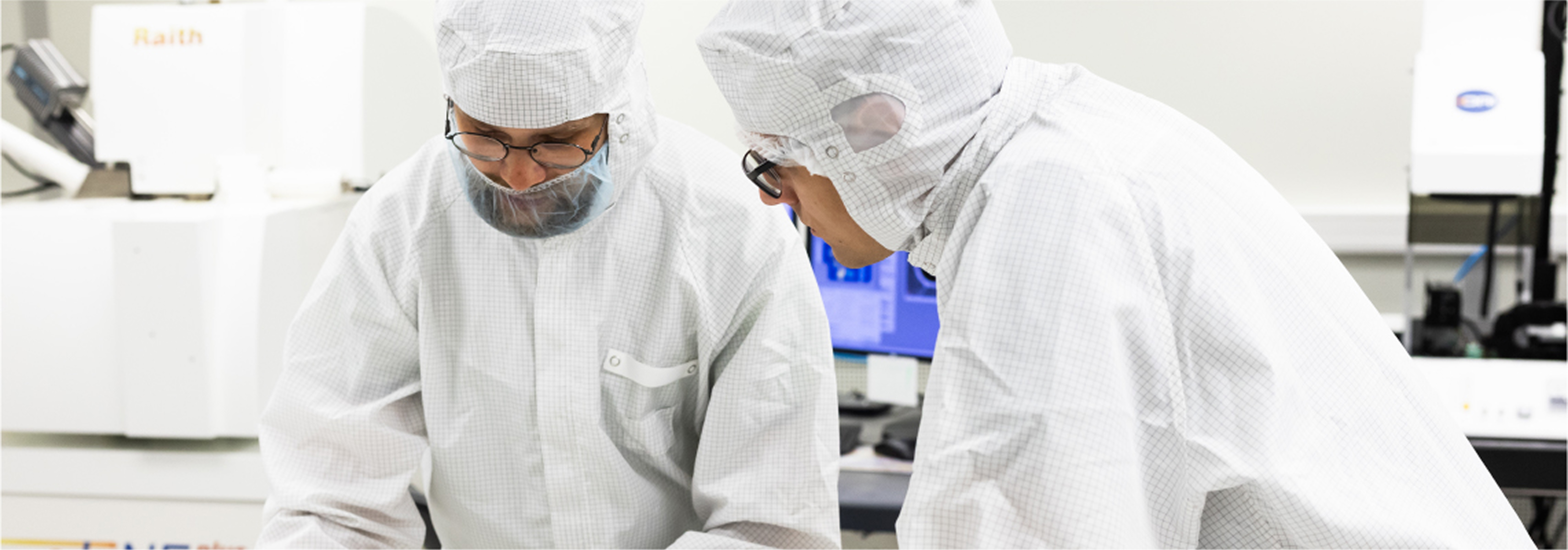 Two KTU researchers wearing cleanroom protective clothing work together in a high-tech laboratory, representing the strategic direction &ldquo;Research and Development for Technological Progress&rdquo;.