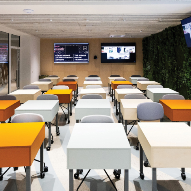 Enabling Environment Modern KTU learning space with movable desks, digital screens and a green plant wall, illustrating a flexible and empowering environment for learning, collaboration and innovation.